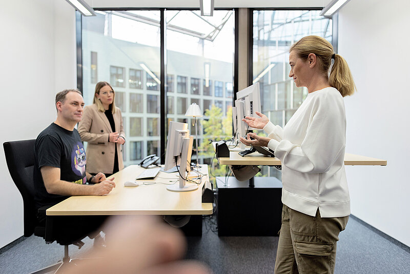 3 Personen unterhalten sich in einem Büro