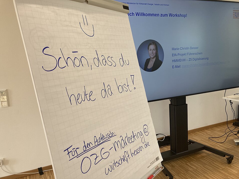 Blick auf ein Flipchart mit Schriftzug "Herzlich Willkommen"