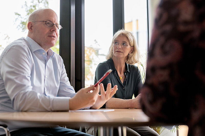 2 Personen sitzen im Gespräch an einem Tisch